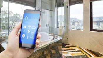 Badezimmer mit einer Hand die ein Smartphone hält, die eine Steuerung einer Lueftung-Klima-App zeigt.